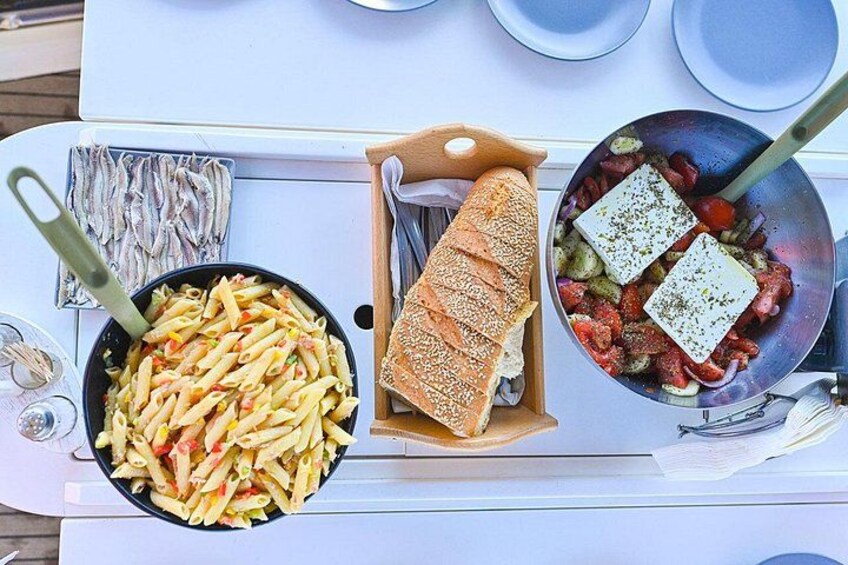 Een tafel met pasta, brood en een pan met groenten en kaas. 2