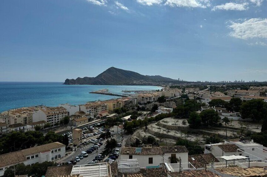 Un paisaje urbano costero con edificios, una carretera y una montaña al fondo. 4
