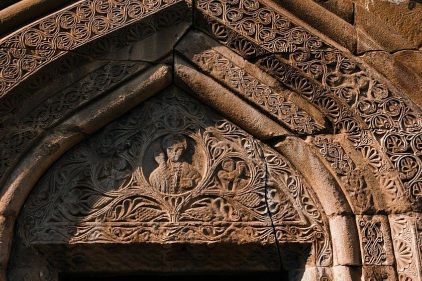 Een stenen boog met gedetailleerde gravures en een centrale figuur. 4