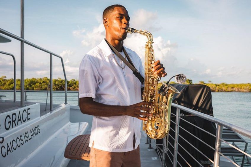 Une personne joue du saxophone sur un bateau, sur lequel on peut lire les mots « GRACE » et « ÎLES CAÏCOS ». 2