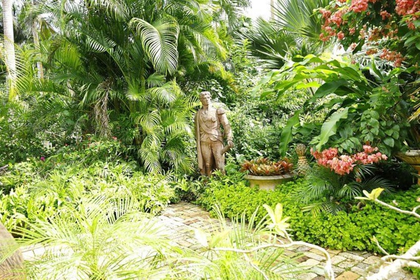 A garden with a statue, lush greenery, and flowering plants. 3