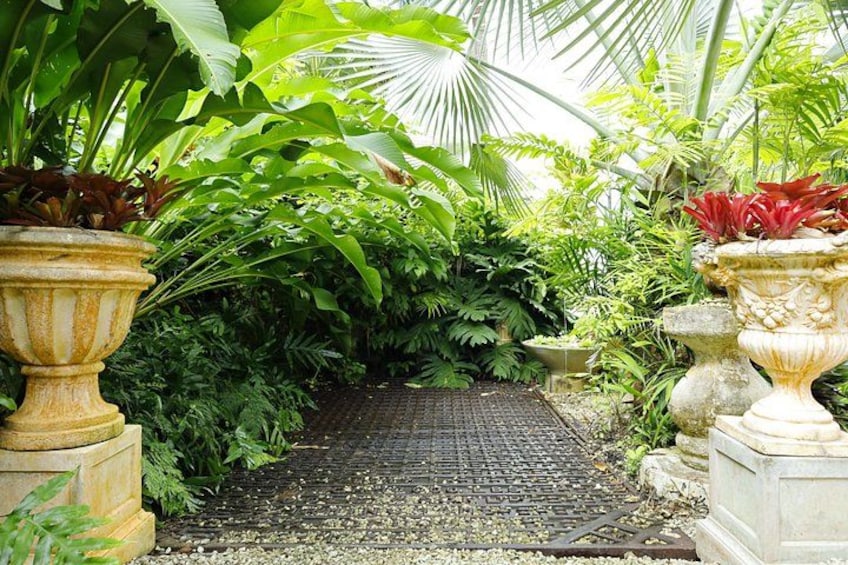 A garden pathway surrounded by lush greenery and ornate planters. 4