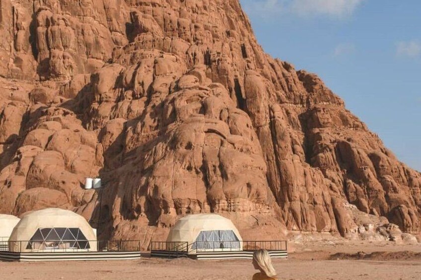 A desert landscape with a large rock formation and several dome-shaped structures. 2