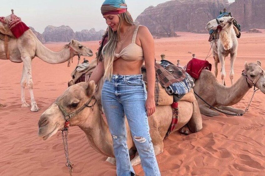 A person standing between camels in a desert landscape. 3