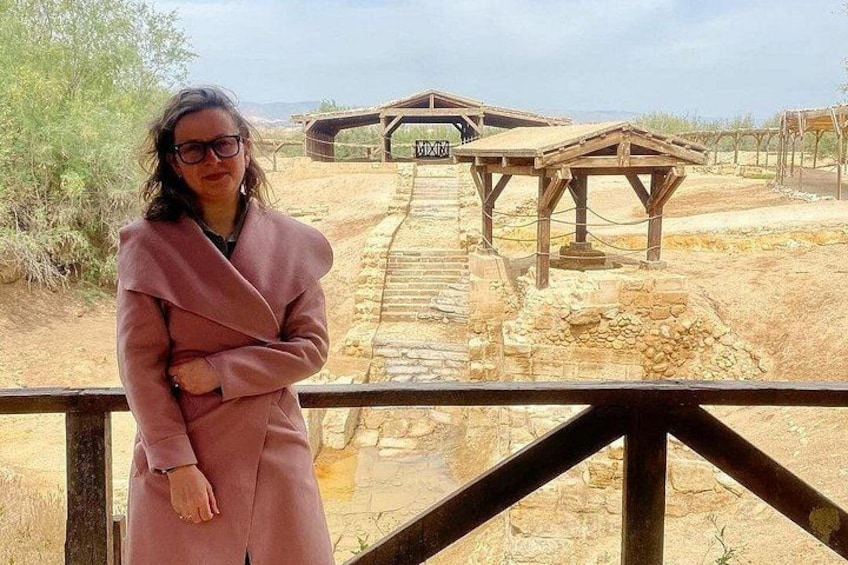 A person standing on a wooden bridge with stone walls and a wooden structure in the background. 3