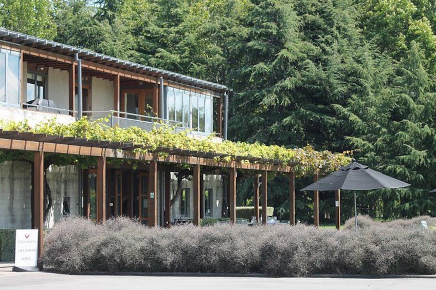A modern building with a covered outdoor area, surrounded by dense greenery. 2