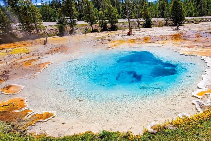 A geothermal hot spring with a blue center surrounded by mineral deposits. 2