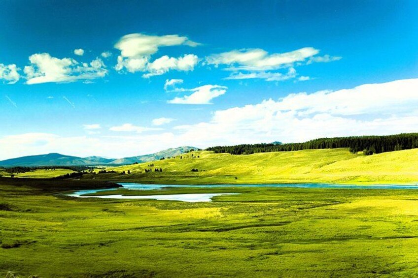 A green landscape with a river, hills, and a clear sky. 3