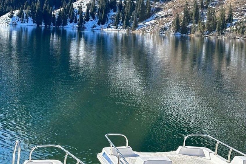 A calm lake with snow-covered trees and a boat dock. 2