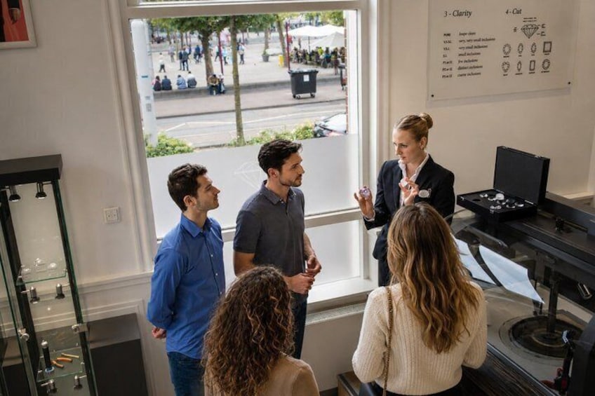 A group of people in a jewelry store, a display case with items, and a window with a view of the street. 1
