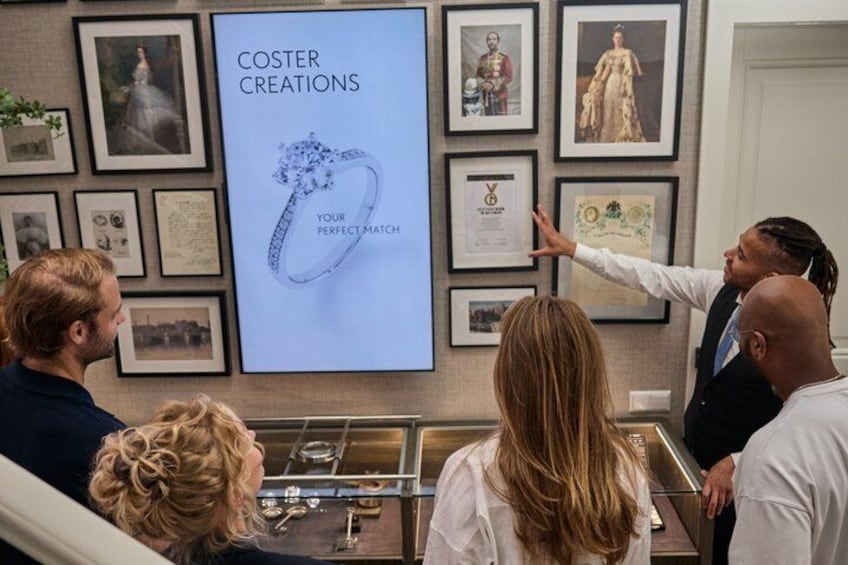 A jewelry display with framed items and a poster reading 'COSTER CREATIONS YOUR PERFECT MATCH'. 3