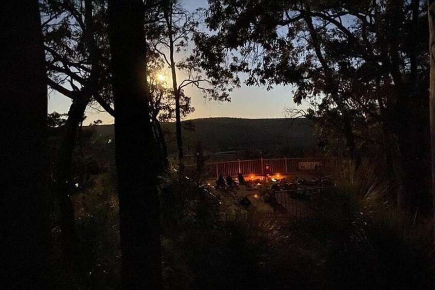 A campfire in a wooded area with trees and hills in the background. 3