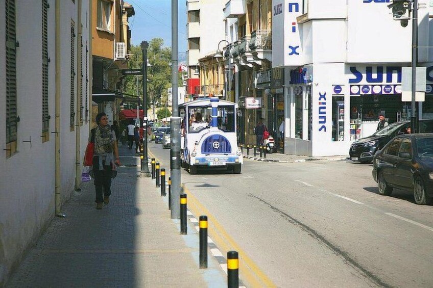A street with a bus, buildings, and a pedestrian. 3