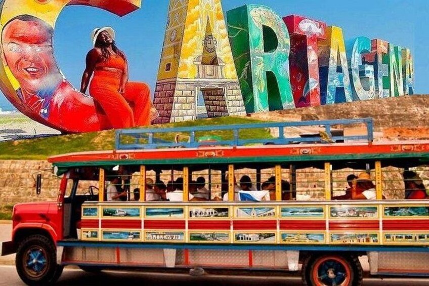 A colorful bus with a mural of a woman in a red dress and the word 'CARTAGENA' in the background. 1