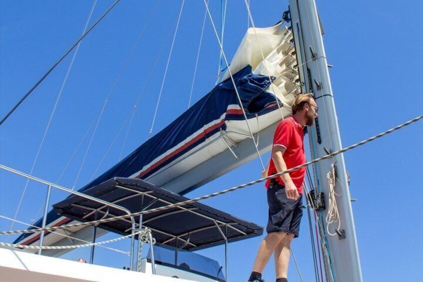 Une personne se tient sur le pont d’un voilier, les voiles et le gréement étant bien visibles. 3