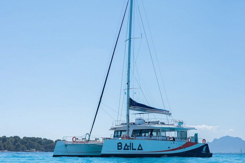 A sailboat with the name 'BAILA' on its side, sailing on blue water with a clear sky. 3