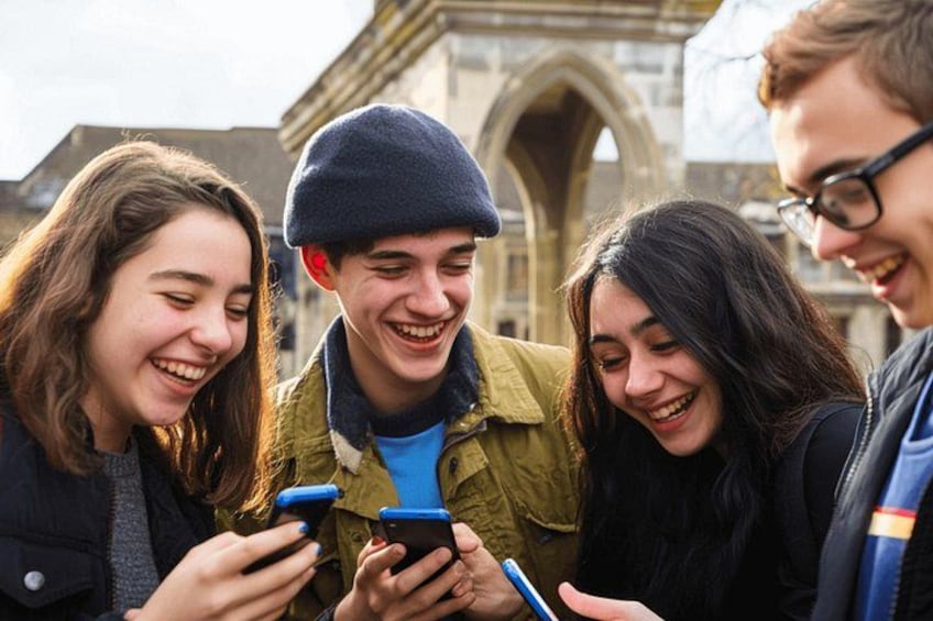 A group of people standing outdoors, looking at a smartphone. 4