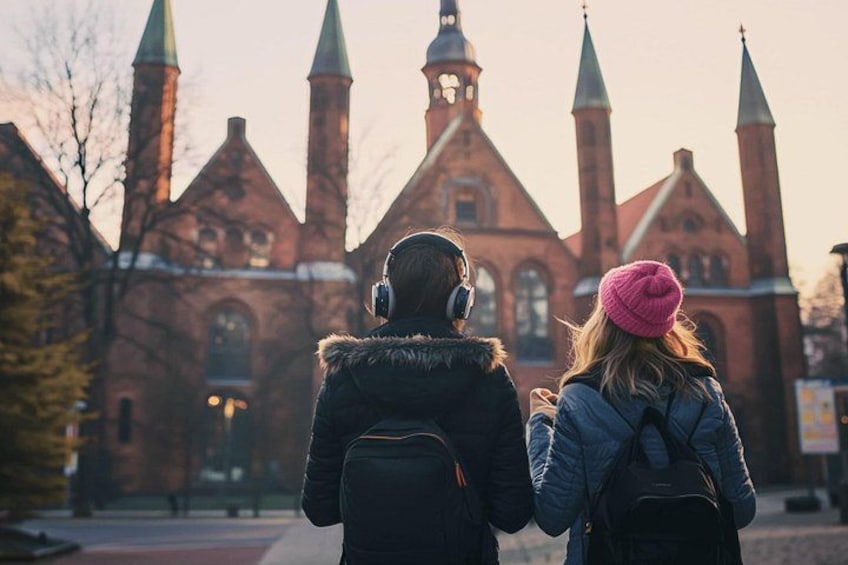 Two people walking towards a historic church with multiple spires. 2
