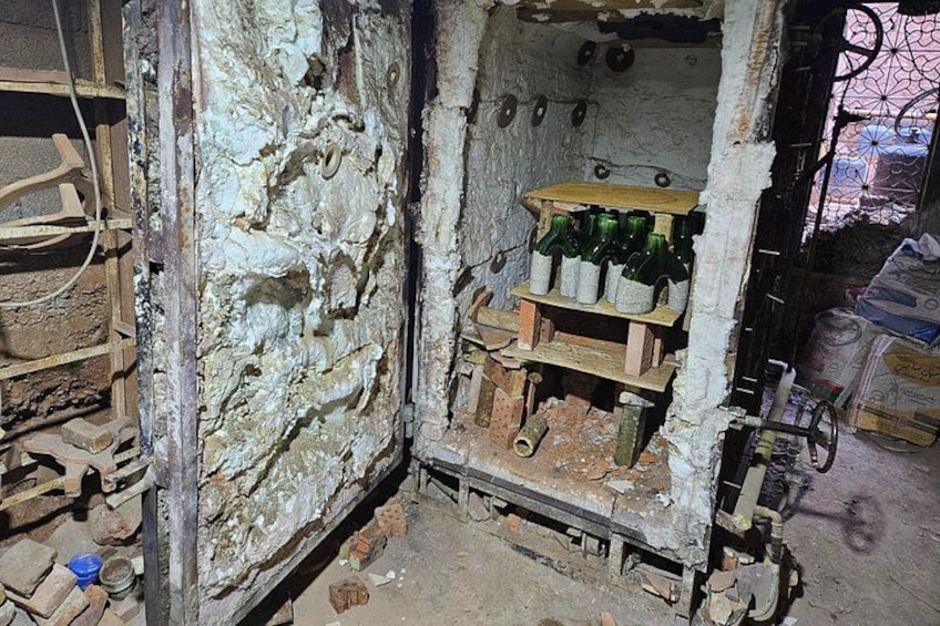 A rustic, cluttered room with a brick wall, shelves with bottles, and scattered debris. 5