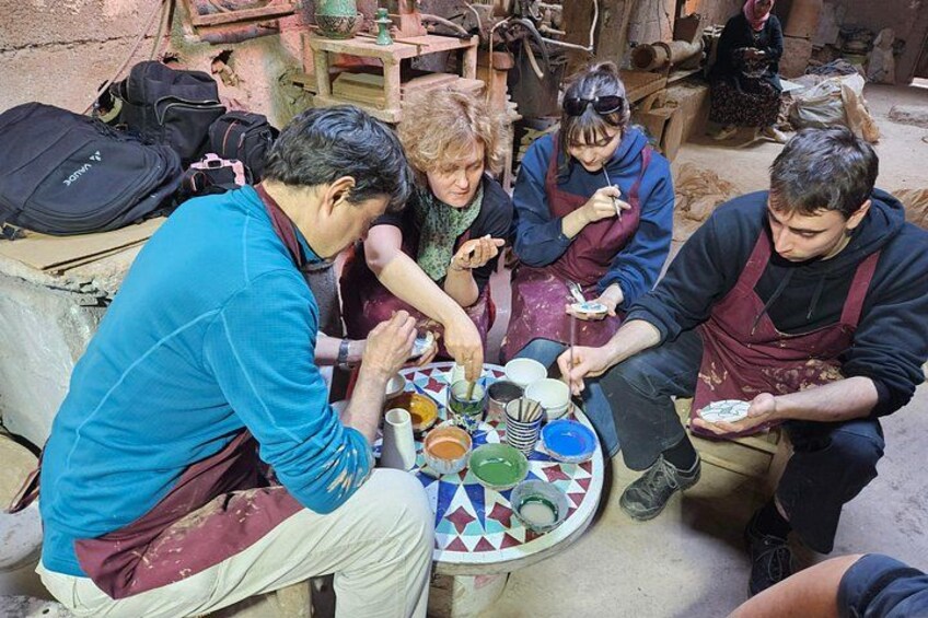 A group of people engaged in pottery making, with various clay items and tools on a table. 4
