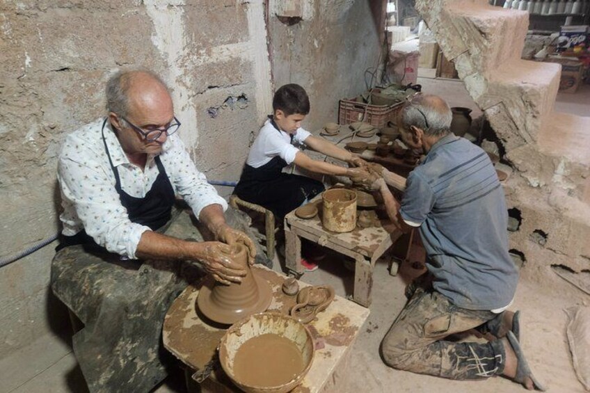 Three people engaged in pottery making, with clay wheels and pottery tools. 1