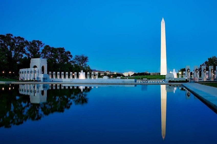 Le Washington Monument se reflète dans une étendue d’eau, entouré d’arbres et sous un ciel dégagé. 4