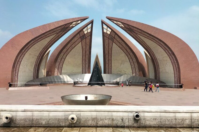 Ein großzügiges, modernes Bauwerk mit geschwungenen, metallischen Bögen und einem zentralen, schwarzen Denkmal. 2
