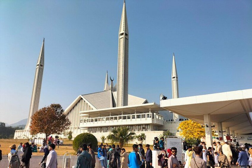 Eine Moschee mit hohen Minaretten und einer großen Menschenmenge vor ihr. 1
