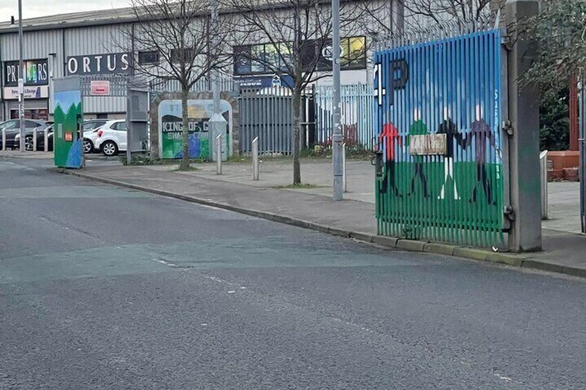 A street with a blue gate, a sign for 'ORTUS', and a parking area. 4