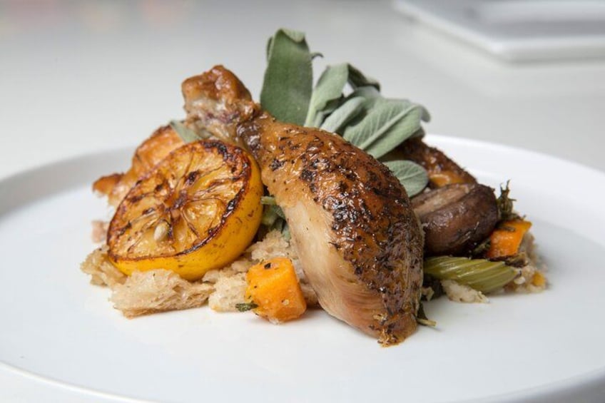 A plate of roasted chicken with vegetables and a lemon slice. 5