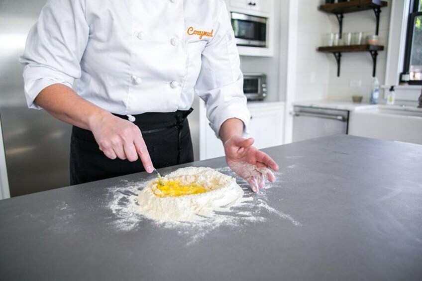 A chef in a white uniform with 'Compal' on the chest, preparing food on a kitchen counter. 2