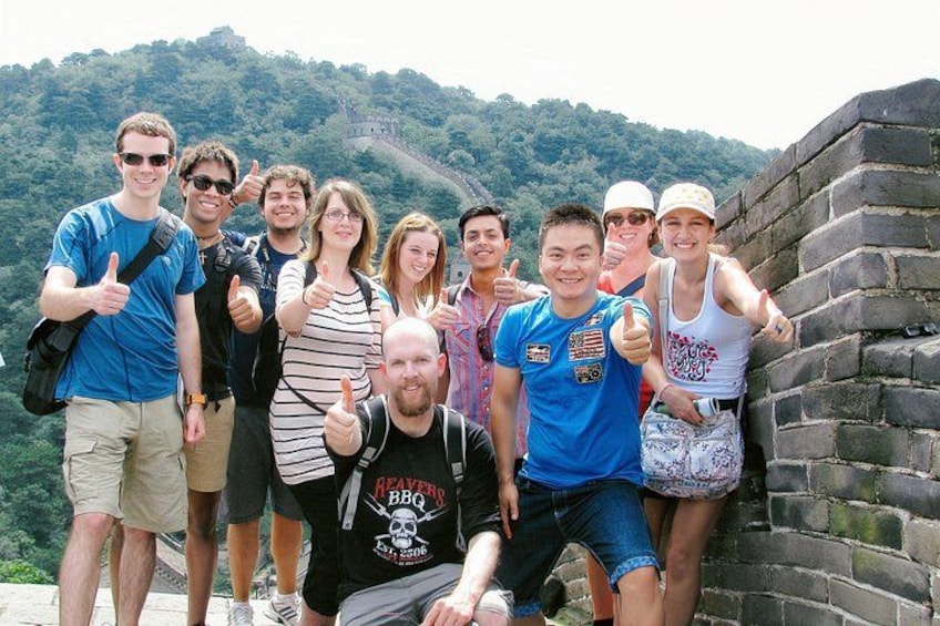 A group of people posing in front of the Great Wall of China. 1