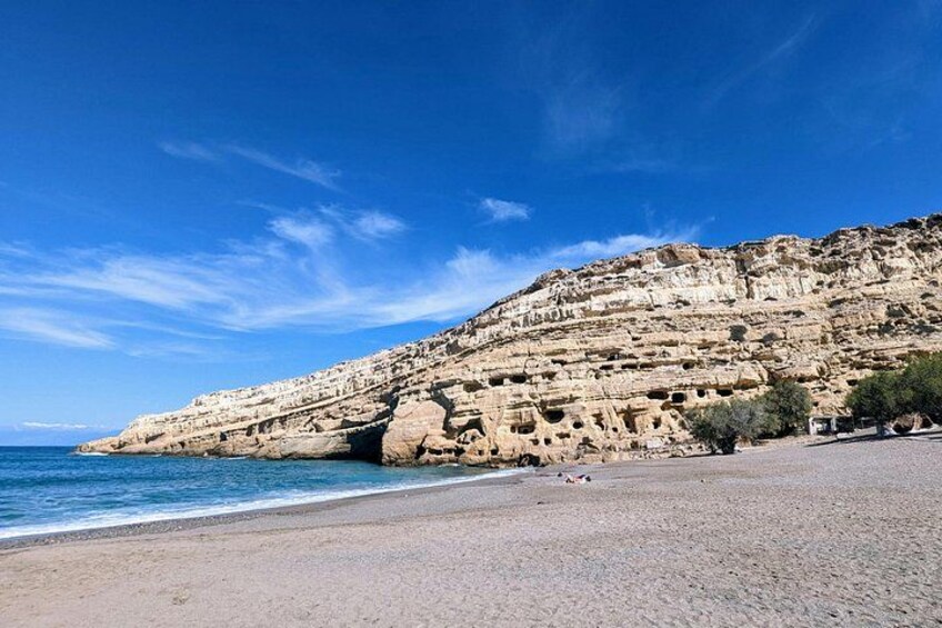 A coastal landscape with a rocky cliff and a sandy beach. 1