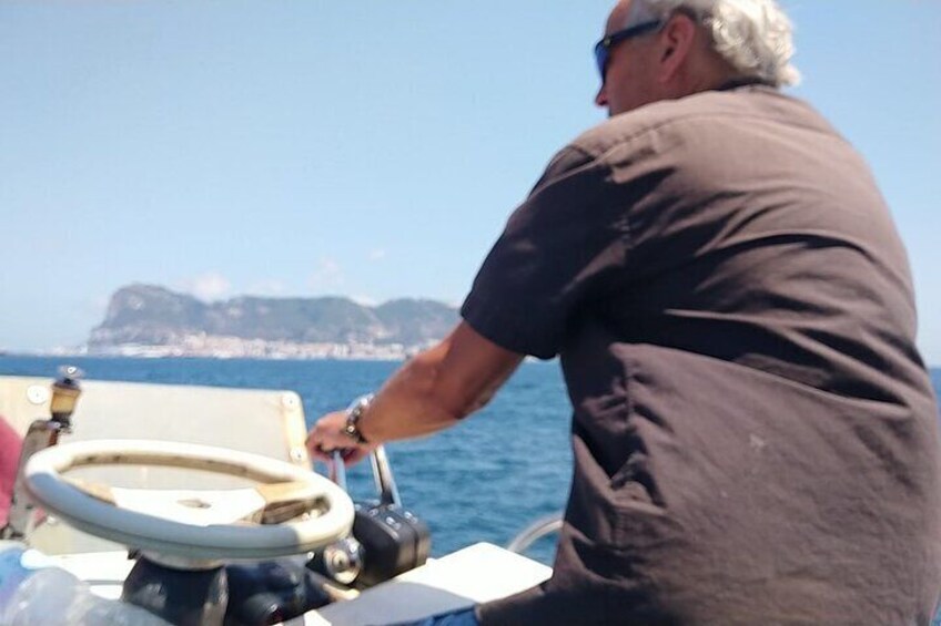 Un hombre timonea un bote con vista despejada al mar y a la costa distante. 1