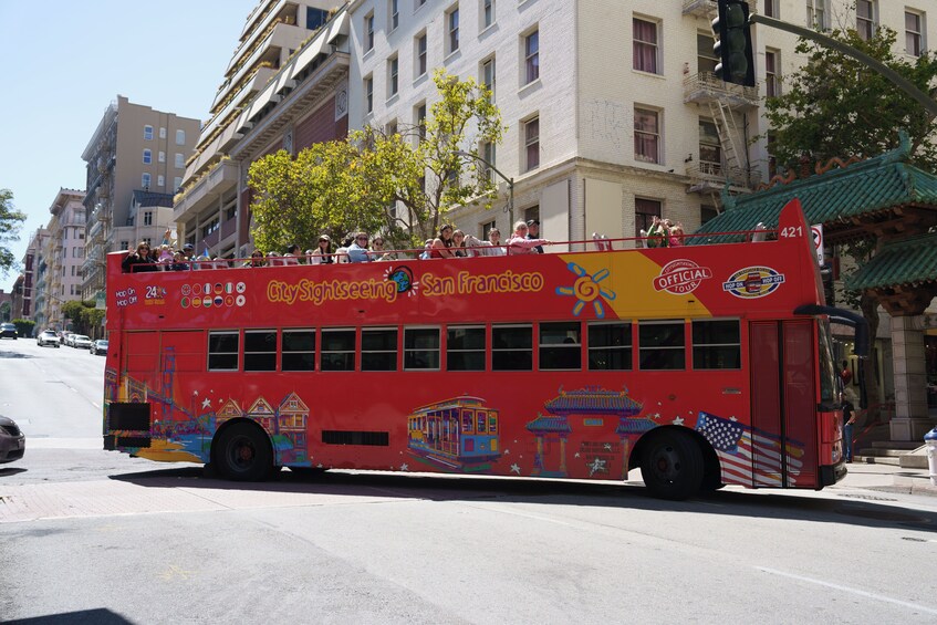 A red double-decker bus with "CitySightseeing San Francisco" written on the side, traveling on a city street. 4