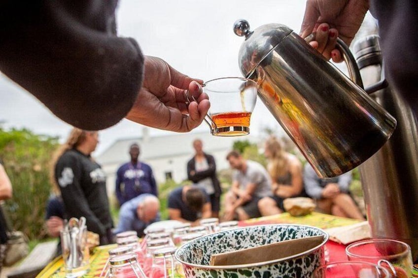 A person pouring a drink from a metal pitcher into a glass. 3