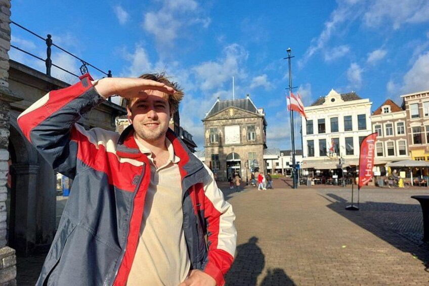 A person standing in a square with historic buildings in the background. 1