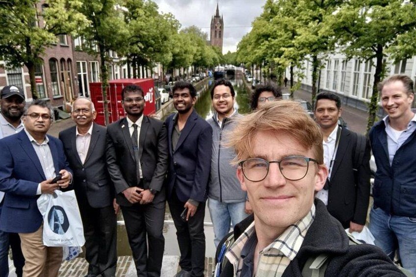 A group of people standing on a street with buildings and a tower in the background. 5