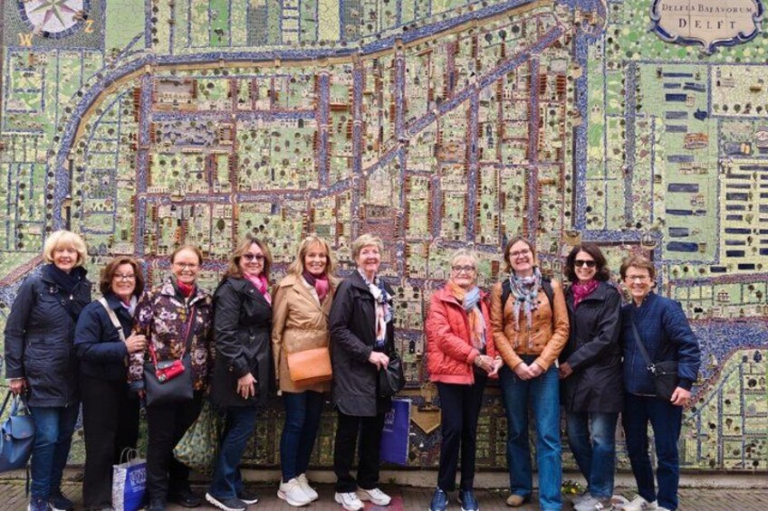 A group of people standing in front of a detailed map mural. 5
