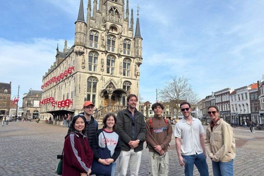 A group of people standing in front of a historic building with a tall tower. 3