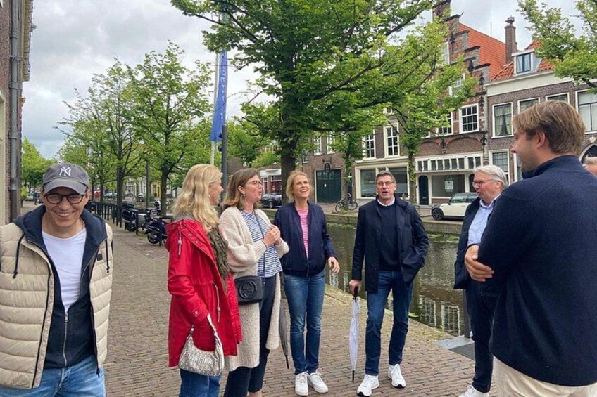 A group of people standing on a cobblestone street with a canal in the background. 2