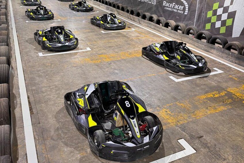 Une piste de course de karting avec plusieurs karts alignés sur la ligne de départ. 3