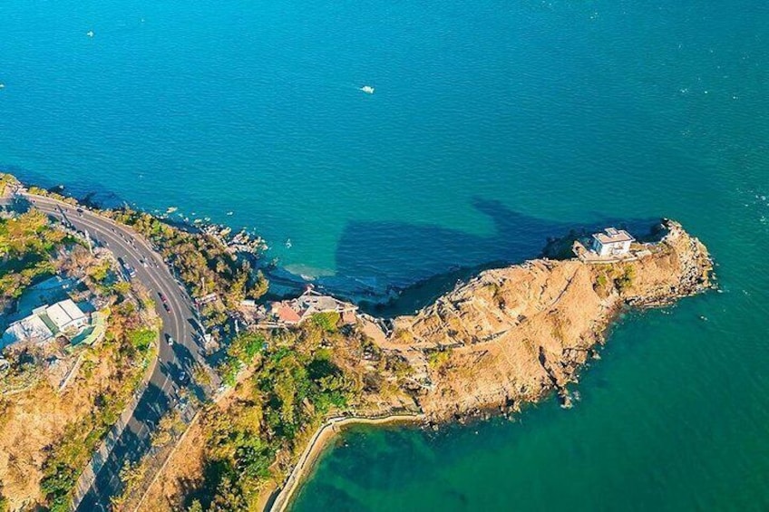 Vista aérea de una zona costera con un camino sinuoso, terreno rocoso y aguas azul turquesa. 2