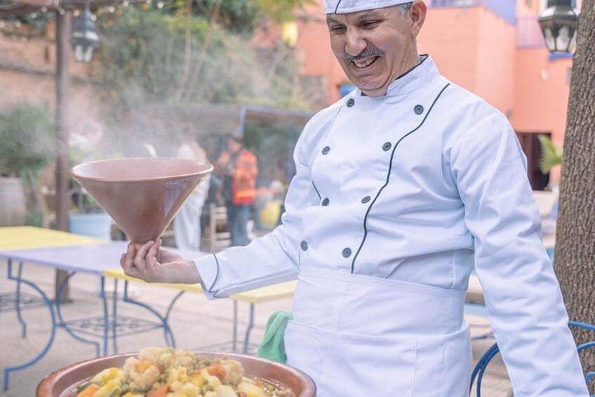 A chef in a white uniform holding a large funnel, likely for serving food. 3