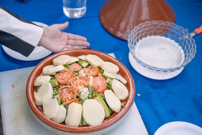 A large terracotta bowl filled with sliced vegetables and cheese on a blue tablecloth. 5