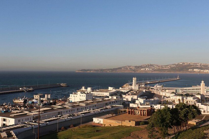 A coastal cityscape with a prominent white building, a pier, and a clear sky. 1