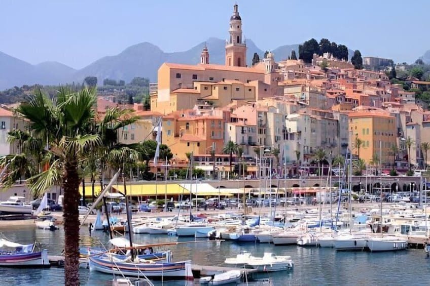 Una cittadina costiera con un porto turistico, imbarcazioni e una torre imponente. 4