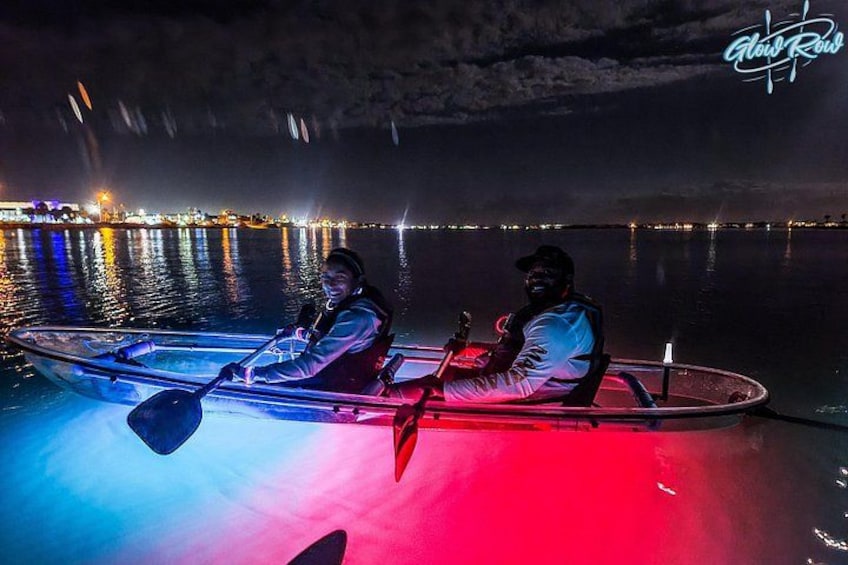 Dos personas en kayak sobre aguas oscuras con luces de colores. 3