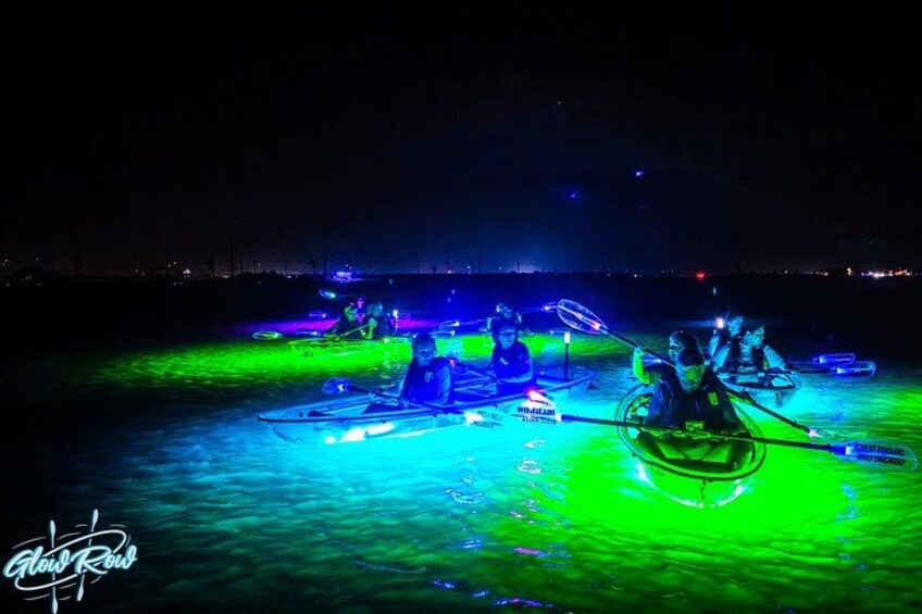 A nighttime rowing event with illuminated boats on water. 3