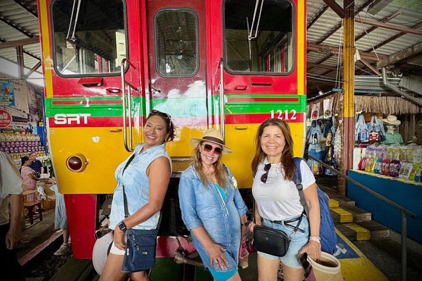 Three people standing in front of a colorful bus with the number 1212. 5